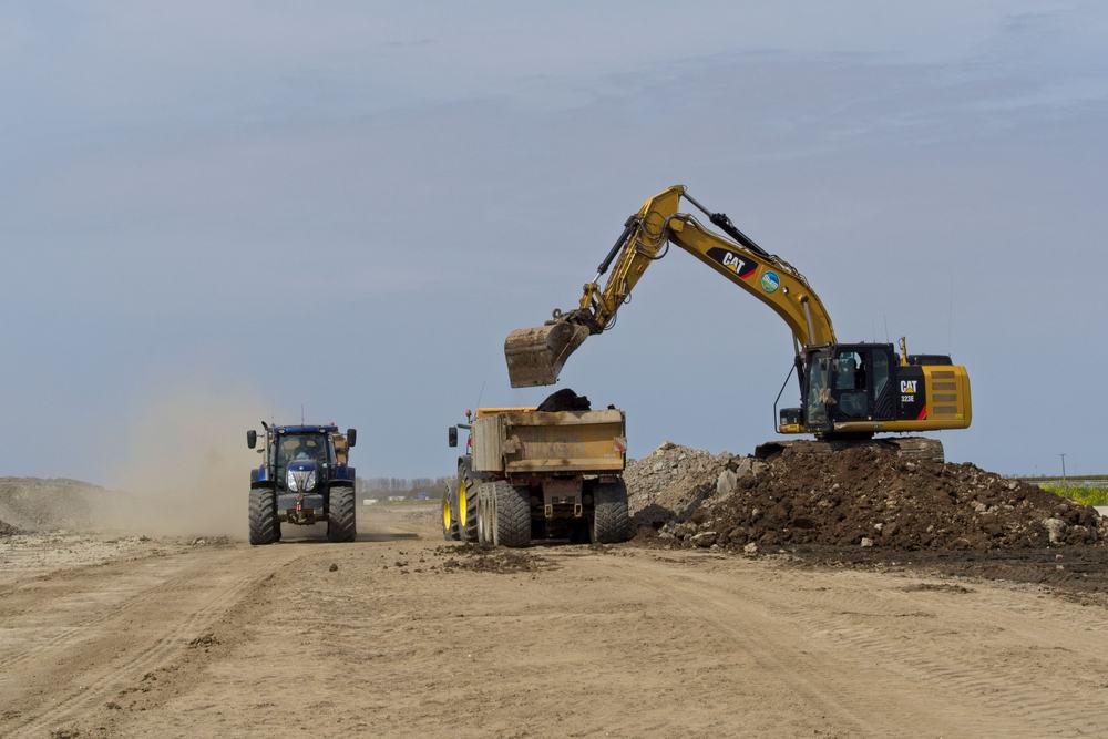 Excavator loading a dump truck on a graded site